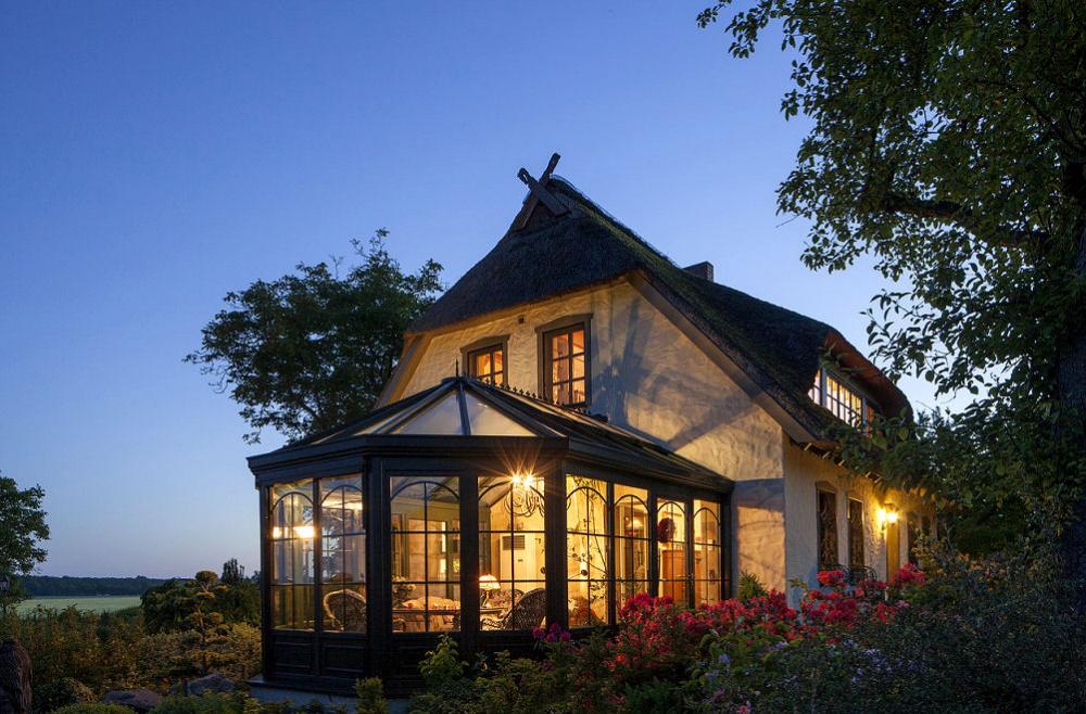 Große Fenster eines Wintergarten verbinden Haus und Garten