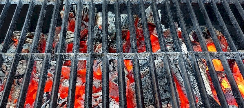 Die glühende Holzkohle scheint geradezu auf das saftig tropfende Fleisch zu warten.